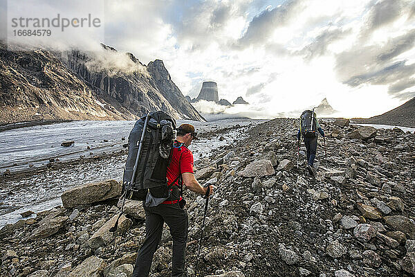 Zwei Rucksacktouristen wandern über eine Gletschermoräne  um die vor ihnen liegenden Berge zu erreichen.