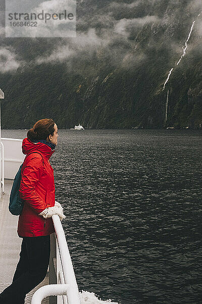Eine Frau starrt auf die natürliche Schönheit des Milford Sound in Neuseeland.