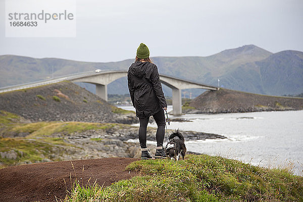 Ein Mensch und sein Hund mit Blick auf das Meer in Norwegen