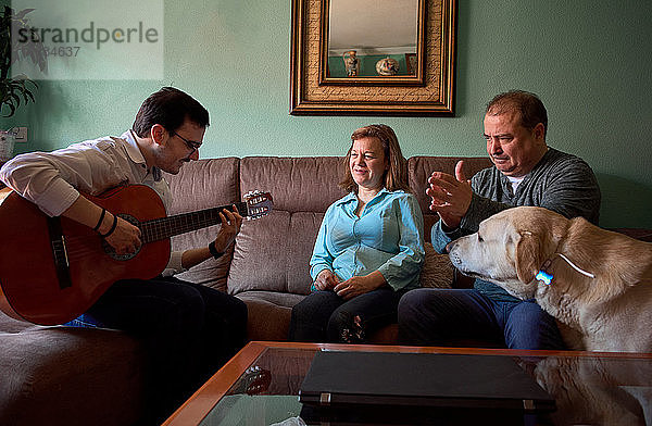 Die Familie hat Spaß  während sie zu Hause Gitarre spielt und singt