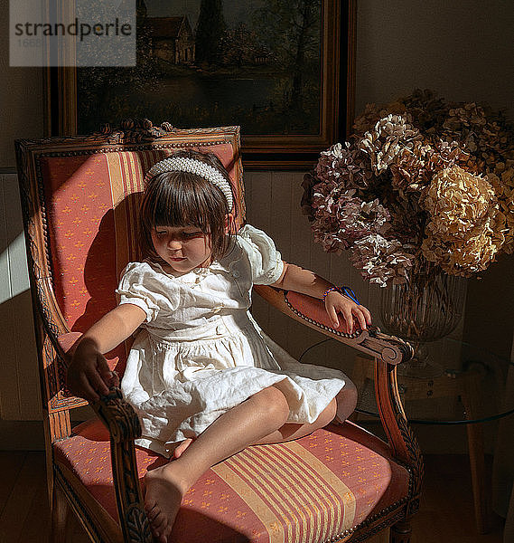 Porträt eines auf einem Stuhl sitzenden Mädchens