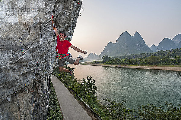 Mann beim Klettern am Flussufer in Yangshuo  einem Klettermekka in China