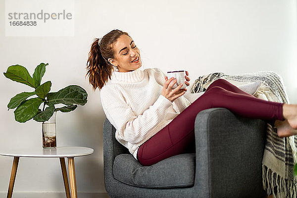 Frau genießt Kaffee in ihrem Stuhl liegend