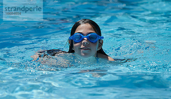 Happy lächelnd Mädchen Schwimmen und Spaß haben im Pool mit blauem Wasser
