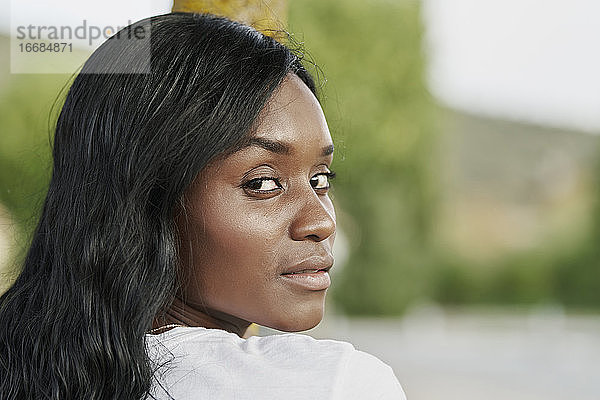 Schöne schwarze Frau schaut in einem Park in die Kamera