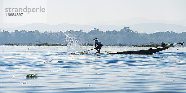 Fischer fängt mit einem Paddel Fische vom Boot aus  Inle-See  Nyaungshwe  Myanmar