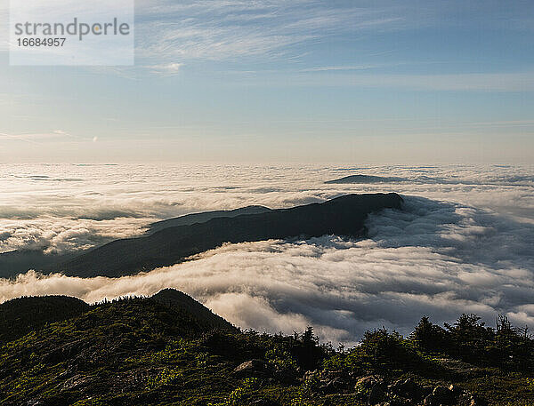 Bigelow Mountain erhebt sich bei Sonnenaufgang in Maine aus einem Meer von Nebel und Dunst