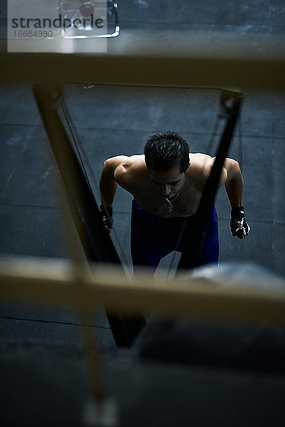 Hemdfreier fitter junger Mann  der im Fitnessstudio drinnen an der Skimaschine trainiert