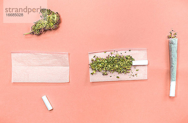 Schritte und Materialien zum Drehen eines Marihuana-Joints auf rosa Hintergrund.