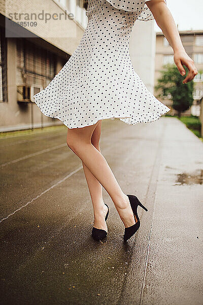 Frau im Polka-Dot-Kleid tanzt im Regen