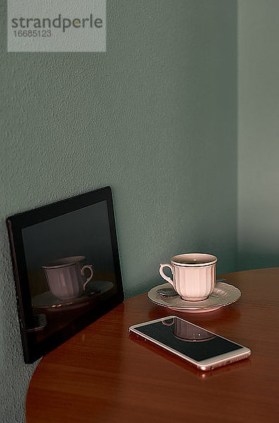 Kaffeetasse  Telefon und ein Tablet auf einem Ecktisch. Konzeptuelles Bild