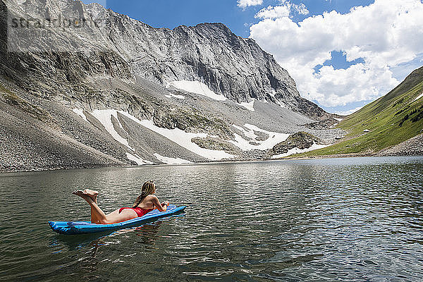 Frau entspannt sich auf einem Floß im See vor einem Berg