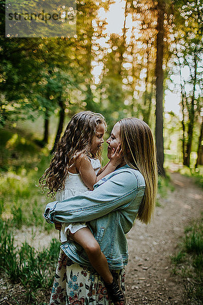 Glückliche Mutter hält junges Mädchen im Wald