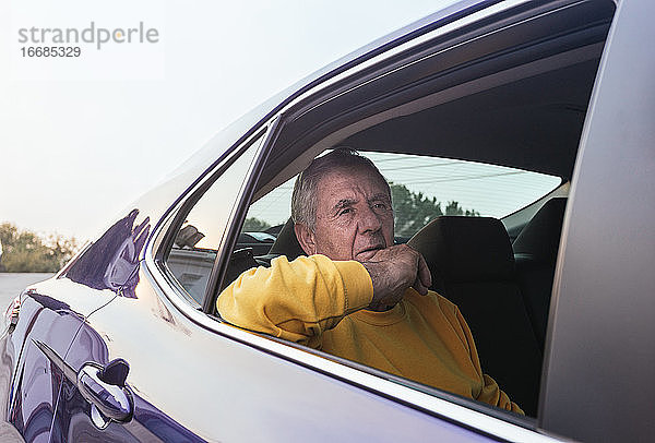 Ein alter Mann sitzt auf dem Rücksitz eines Elektroautos