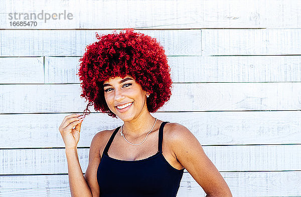 Porträt einer Frau mit rotem Afro-Haar auf weißem Hintergrund.