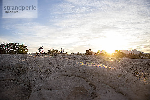 Eine Frau auf einer Fahrradtour bei Sonnenaufgang auf Gooseberry Mesa  Utah