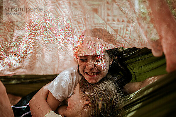 Lachende und sich umarmende Teenager-Mädchen im Zelt