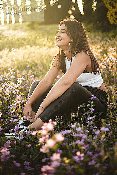 Glücklicher Teenager  der bei Sonnenuntergang auf einem Feld zwischen Blumen lacht
