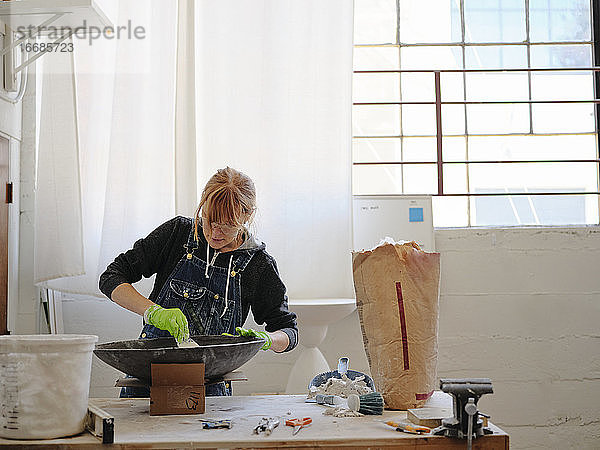 Professionelle Bildhauerin bei der Arbeit mit Gips in ihrem Atelier