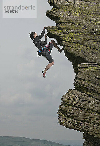 Frau beim Klettern an den Windgather-Felsen im britischen Peak District