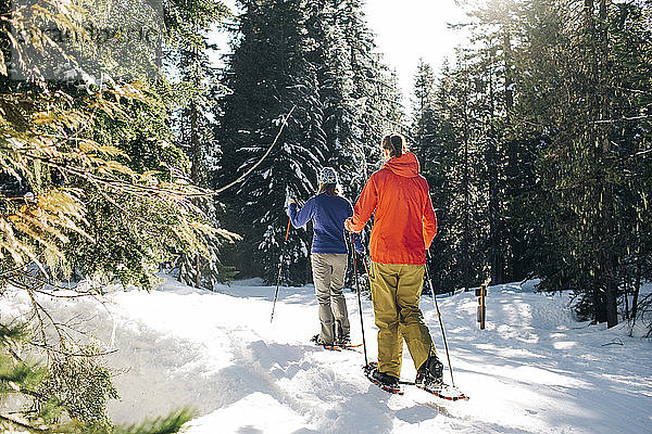 Zwei junge Frauen gehen an einem sonnigen Tag auf dem Mt. Hood Schneeschuhlaufen.