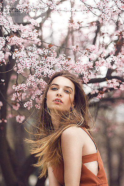 Modeporträt einer jungen Frau vor einem Kirschblütenbaum