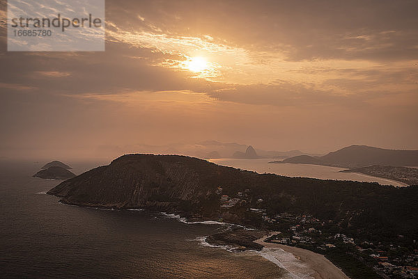 Schöner Blick auf den Sonnenuntergang von der Hügelspitze auf das Meer  den Strand und die orangefarbenen Wolken