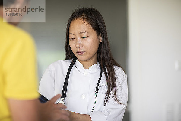 junge Asiatin Ärztin Frau mit Patientin Bericht in einer Praxis