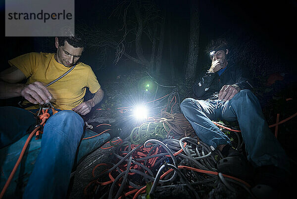 zwei Männer  die im Dunkeln nach einer Klettertour ihre Kletterausrüstung organisieren