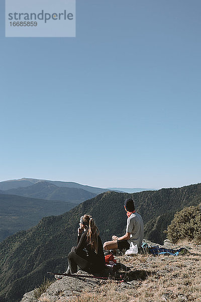 Mädchen und Junge in den Bergen  die beim Ausruhen die Landschaft beobachten