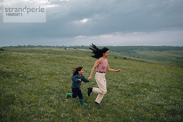 Mutter und Tochter laufen in der Natur einen Hügel hinunter