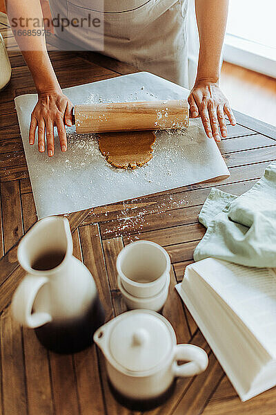 Hände rollen Teig für Kekse auf einem Tisch aus  Ansicht von oben