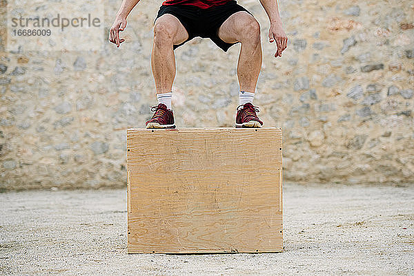 Ein Mann übt Crossfit und springt in eine plyometrische Box.