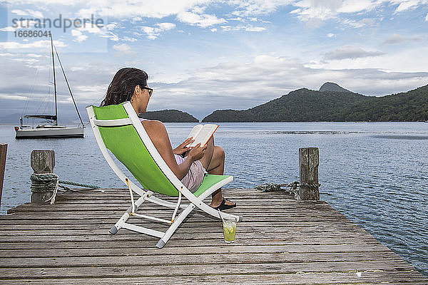 Frau entspannt sich am Pier auf der tropischen Insel Ilha Grande