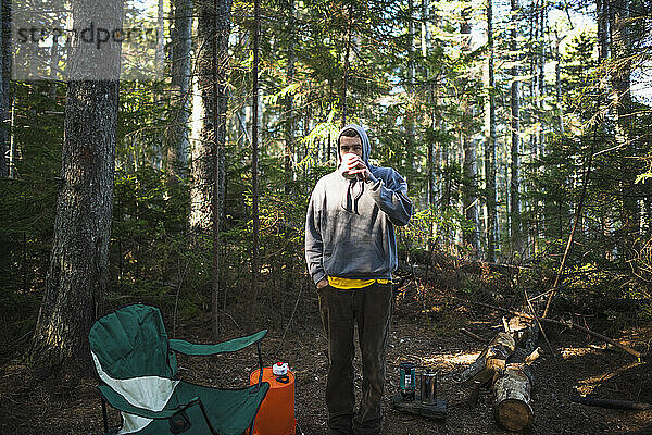 Solo-Mann trinkt Kaffee beim Camping an der Küste von Maine