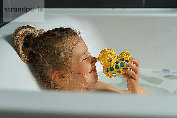 Porträt eines lächelnden jungen Mädchens in der Badewanne mit einer Gummi-Ente.