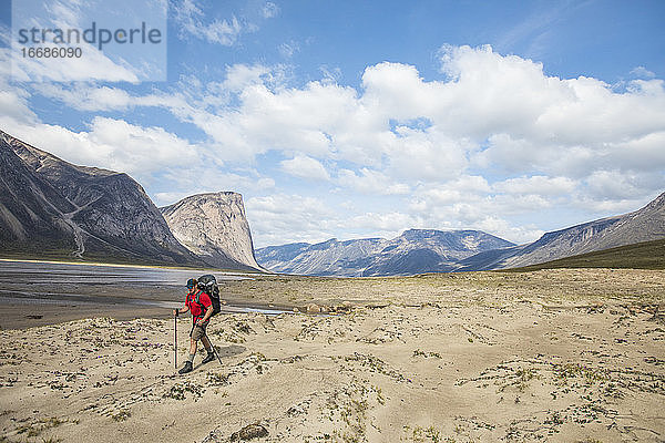 Mann beim Wandern neben dem Owl River am Akshayak Pass