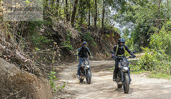 zwei Freunde fahren mit ihren Scrambler-Motorrädern durch den Wald