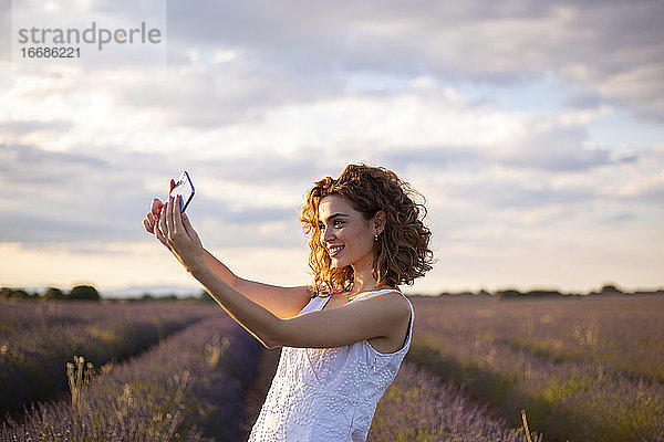 Frau mit Mobiltelefon in einem Lavendelfeld