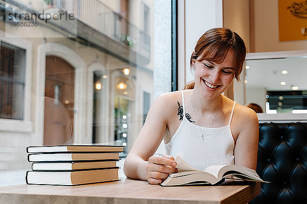 Junge Frau liest Bücher in einem Café