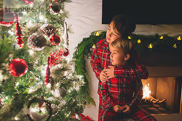 Zwei Brüder betrachten nachts den Weihnachtsbaum zu Hause