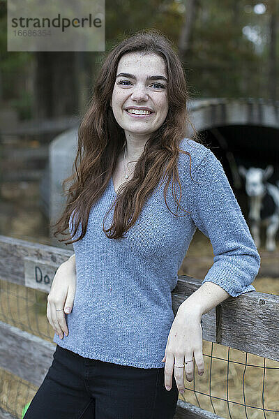 Porträt eines hübschen Teenagers  der in einem Ziegenstall auf einem Bauernhof lächelt