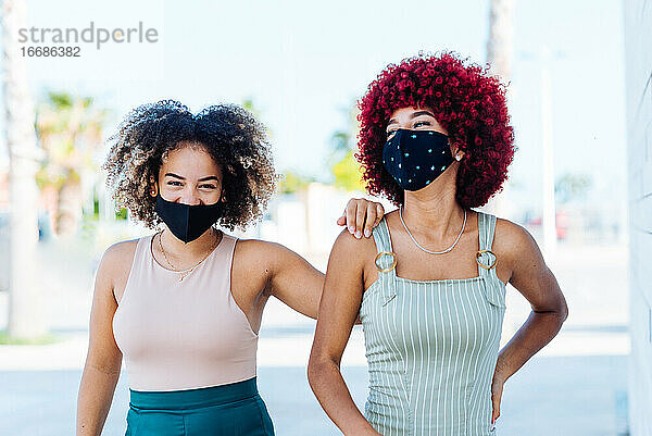 Zwei lateinamerikanische Frauen mit Schutzmaske in unbekümmerter Haltung.