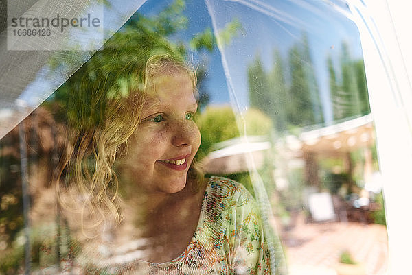 Mädchen in einem Wohnwagen auf einem Campingplatz. Sie schaut durch das Fenster.