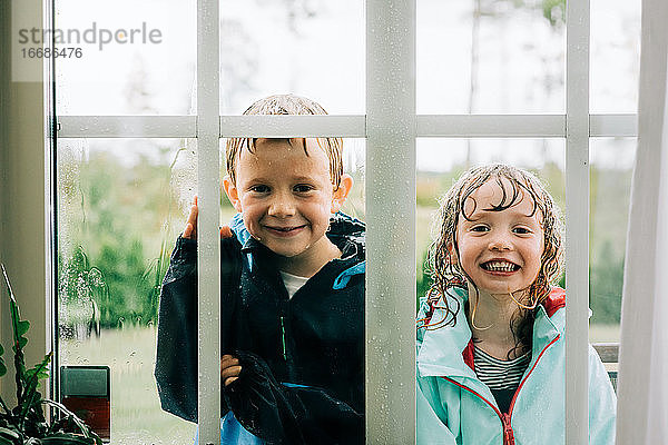 Bruder und Schwester standen beim Spielen und schauten durch ein Fenster