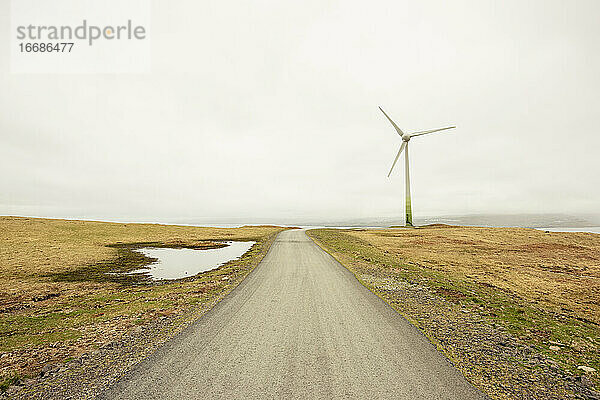 Straße und Windmühle vor grauem Himmel