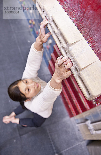 Frau trainiert am Griffbrett in der Kletterhalle