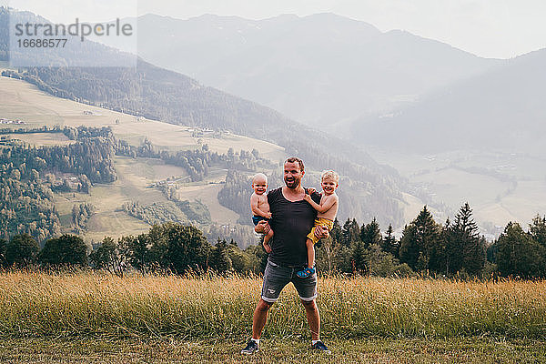 Vater und Kinder lächeln in die Kamera während der Ferien in den Alpen
