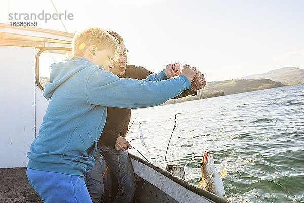 Mann und Junge fischen zusammen auf einem Boot