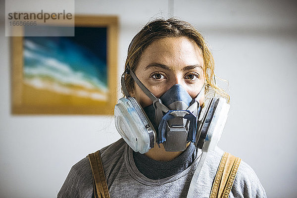 Porträt einer Harzkünstlerin in einem selbstgebauten Atelier mit Atemschutzmaske